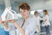 Ориентированная женщина-архитектор рассматривает модель в офисе — стоковое фото