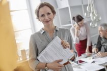 Portrait smiling businesswoman with paperwork in office meeting — Stock Photo
