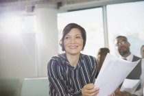 Улыбающаяся деловая женщина с бумажной работой в конференц-зале — стоковое фото