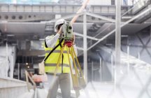 Male engineer using theodolite at construction site — Stock Photo