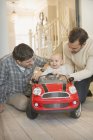 Male gay parents and baby son playing with toy car — Stock Photo