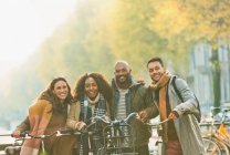 Ritratto sorridente amici in bicicletta sulla strada urbana di autunno — Foto stock