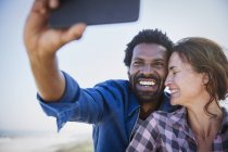 Cariñosa, feliz pareja multiétnica tomando selfie con el teléfono de la cámara - foto de stock