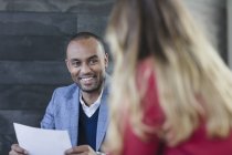 Lächelnder Geschäftsmann mit Papierkram im Gespräch mit Geschäftsfrau bei einem Treffen — Stockfoto