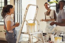 Friends drinking coffee and painting living room — Stock Photo
