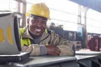 Портрет улыбающийся, уверенный сталевар за ноутбуком на сталелитейном заводе — стоковое фото