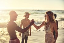 Verspieltes junges Paar High-Fiving am sonnigen Sommer-Ozeanstrand — Stockfoto
