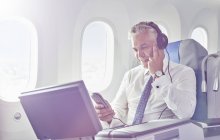 Homme d'affaires avec écouteurs regardant un film dans l'avion — Photo de stock