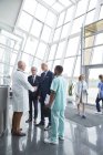 Male surgeon greeting, shaking hands with administrator businessmen in hospital lobby — Stock Photo