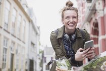 Retrato entusiasta mujer joven en bicicleta mensajes de texto en la calle de la ciudad - foto de stock