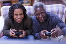 Happy grandfather and grandson playing video game — Stock Photo