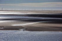 Wind turbines in distance beyond bay, Morecambe Bay, UK — Stock Photo