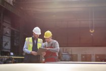 Male foreman and worker with clipboard talking in factory — Stock Photo