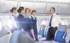 Pilotos e comissários de bordo conversando, preparando-se no avião — Fotografia de Stock