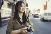Sonriente joven turista fotografiando con cámara en calle urbana - foto de stock