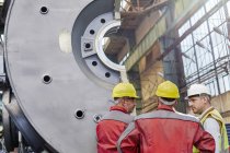 Рабочие-мужчины говорят на сталелитейном заводе — стоковое фото
