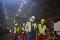 Supervisore e lavoratori siderurgici che camminano e parlano in acciaieria — Foto stock