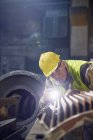 Фокусований сталевий працівник з ліхтариком, що вивчає сталеву частину в сталеливарному заводі — стокове фото