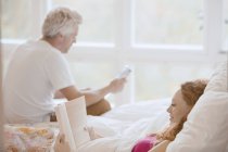 Paar liest Buch und digitales Tablet im Bett — Stockfoto