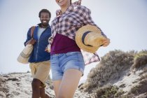 Sorridente, coppia entusiasta a piedi sul sentiero soleggiato spiaggia di sabbia estiva — Foto stock