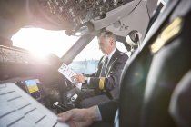 Pilotos masculinos com prancheta se preparando no cockpit do avião — Fotografia de Stock