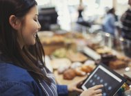 Smiling cashier using touch screen cash register in cafe — Stock Photo