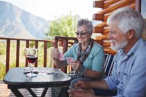 Active senior couple drinking wine and playing cards on cabin balcony — Stock Photo