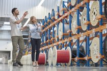 Руководители мужского и женского пола проверяют инвентаризацию на заводе волоконной оптики — стоковое фото