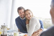 Happy affectionate couple laughing and hugging at patio breakfast — Stock Photo