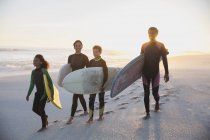 Surfeurs familiaux portant des planches de surf sur la plage estivale du coucher du soleil — Photo de stock