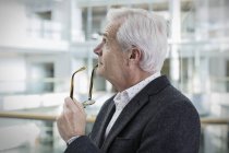 Pensive businessman looking up at modern office — Stock Photo