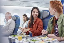 Women friends eating dinner and talking on airplane — Stock Photo