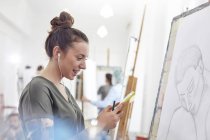 Smiling female artist with headphones listening to music and sketching in art class studio — Stock Photo