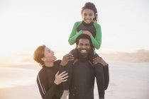 Ritratto famiglia sorridente in mute sulla spiaggia estiva soleggiata — Foto stock