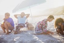 Multiethnische Familie entspannt sich und spielt im Sand am sonnigen Sommerstrand — Stockfoto
