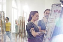 Artisti concentrati che dipingono al cavalletto in studio di arte classe — Foto stock