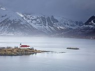 Remote church along fjord waterfront below snowy mountains, Sildpoinesnet, Austvagoya, Norway — Stock Photo