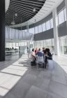 Geschäftsleute treffen sich an einem Tisch im modernen Büro-Atrium — Stockfoto
