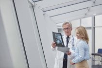 Чоловік-лікар, який показує рентгенівський знімок пацієнта у лікарні — стокове фото