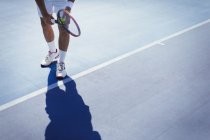Young male tennis player preparing to serve the ball on sunny blue tennis court — Stock Photo