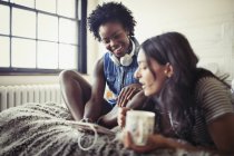 Лесбиянки пьют кофе и используют цифровой планшет на кровати — стоковое фото