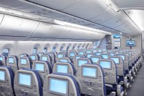 Rows of seats with entertainment screens on airplane — Stock Photo