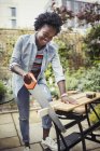 Smiling woman with saw cutting wood on patio — Stock Photo