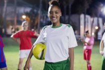 Porträt lächelnde, selbstbewusste junge Fußballerin mit Ball in der Nacht — Stockfoto