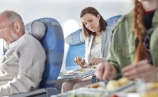 Woman eating dinner on airplane — Stock Photo