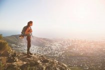 Female rock climber on top of hill overlooking sunny city — Stock Photo