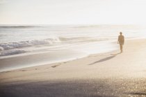 Silhouette femme marchant sur la plage d'été ensoleillée idyllique — Photo de stock