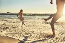 Игривая молодая пара, плескающаяся в солнечном летнем океане — стоковое фото