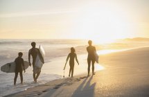 Familien-Surfer spazieren mit Surfbrettern am sonnigen Strand bei Sonnenuntergang — Stockfoto