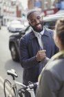 Smiling businessman with bicycle shaking hands with woman on urban street — Stock Photo